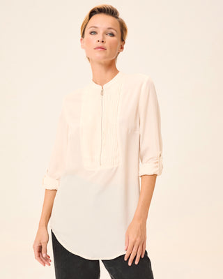 Mujer con blusa beige elegante, vista lateral mostrando los detalles del diseño.