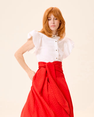 Mujer con blusa blanca, combinada con falda roja anudada a la cintura