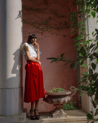 Mujer con blusa blanca, en un entorno decorativo con plantas