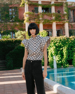 Mujer con blusa con volantes, de pie con fondo arquitectónico elegante