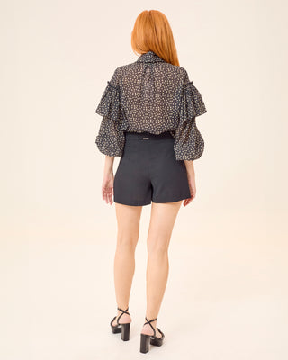 Blusa lunares en imagen de producto sobre fondo gris.