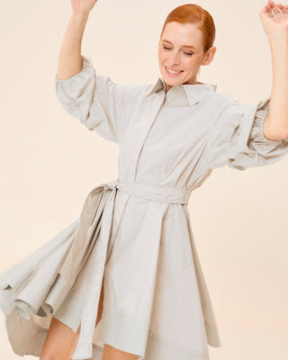 Mujer con vestido corto camisero, posando con movimiento y sonrisa relajada.