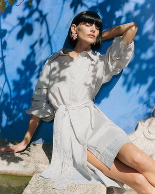 Mujer con vestido corto camisero, vista lateral resaltando la caída fluida del diseño.