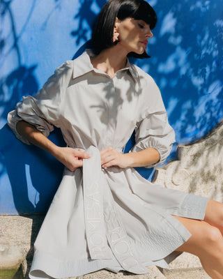 Mujer con vestido corto camisero, caminando con actitud relajada y sofisticada.