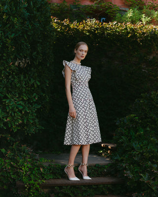 Mujer con vestido estampado geométrico, en un jardín con fondo verde