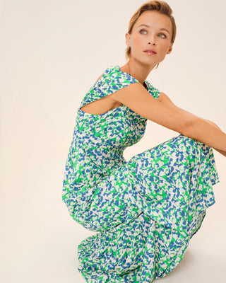 Mujer con vestido verde aguamarina, posando sentada con los brazos extendidos y sonrisa relajada.